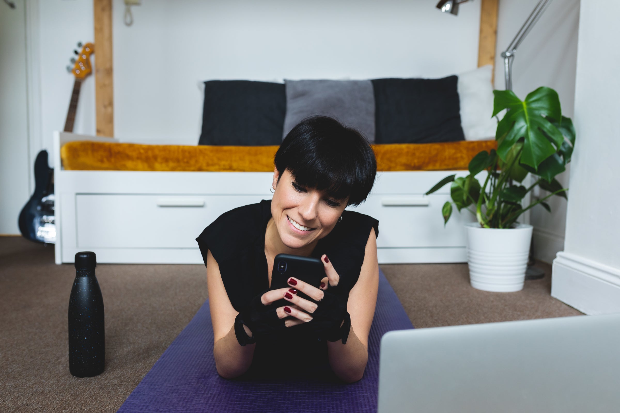 woman-lays-on-a-purple-yoga-mat-looking-at-her-phone - onlygoodstuff.ch